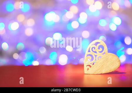 Herz aus Holz in lilakischen Bokeh-Lichtern. Wunderschöner violett-violetter Hintergrund mit Herzen. Webbanner oder Flyer zum Valentinstag, zum Jubiläum Stockfoto