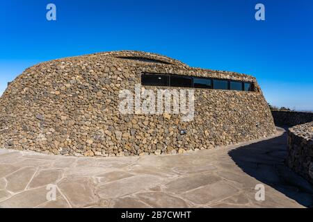 Moderne Öffentliche Architektur. Gebogene schräge Wand aus Stein. The Rock Shed on Sunny Day. Stockfoto