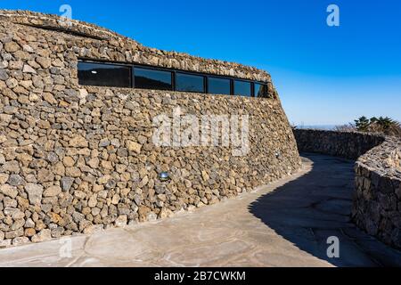Moderne Öffentliche Architektur. Gebogene schräge Wand aus Stein. The Rock Shed on Sunny Day. Stockfoto