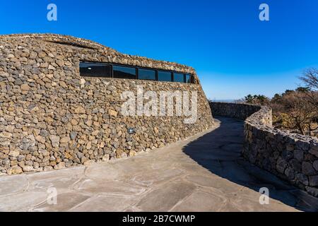 Moderne Öffentliche Architektur. Gebogene schräge Wand aus Stein. The Rock Shed on Sunny Day. Stockfoto