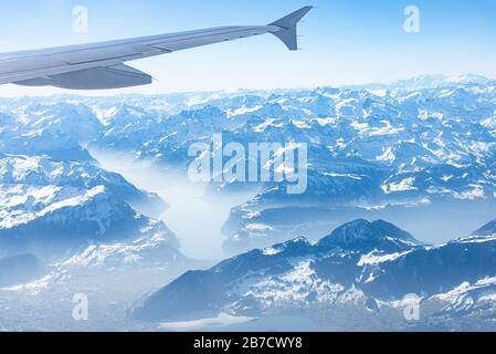 Einzigartiges alpines Luftpanorama. Blauer Planet Erde Höhenflug von einem Flugkabinenfenster aus, das über Zürich fliegt, aus dem Blick auf die Schweizer Alpen Stockfoto