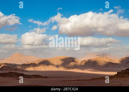 Königreich Jordanien, Wüste Wadi Rum, sonnige Landschaft am Wintertag mit weißen, pfiffigen Wolken und warmen Farben. Schöne Reisefotografie. Schöne Wüste konnte auf Safari erkundet werden. Buntes Bild Stockfoto