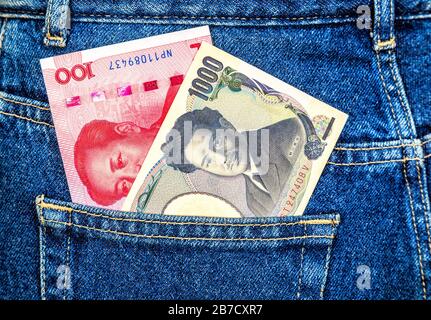 Banknoten von japanischem Yen und chinesischem Yuan, die aus der Jeans-Tasche auf der Rückseite herausragen Stockfoto
