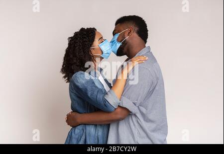 Romantisches Schwarzes Paar Küsst Sich In Medizinischen Schutzmasken Stockfoto