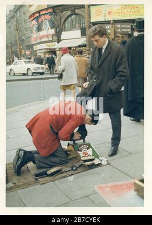 Klassisches Schnappschussbild eines jungen, elegant gekleideten Mannes in einem Anzug, der seine Schuhe in den 1960er Jahren auf den Straßen Londons glänzte und büffelte. Foto soziale Geschichte Vernacular Fotografie Großbritannien gefunden. Fotograf unbekannt (Richard Bradley Kollektion) Stockfoto