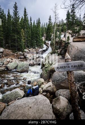 junges kaukasisches Touristenpaar, das den Gletscherbach des Alberta Falls bewundern Rocky Mountain National Park Colorado, USA Stockfoto