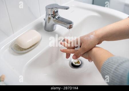Zwei Hände waschen gründlich mit Seife in einem weißen Waschbecken Stockfoto