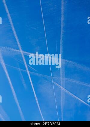 Flugchemtrails in blauem Himmel mit Mond und Wolken Stockfoto