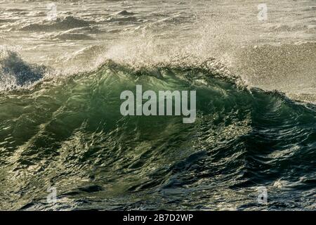 Ein Nahaufnahme einer Welle, die bei Sonnenaufgang bricht, am Strand Marina in Südafrika. Stockfoto
