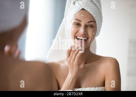 Glückliche Frau, die morgens Hautpflegeprogramm im Badezimmer genießt. Stockfoto