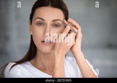 Junge schöne Frau, die Augenbrauen raut und die Kamera betrachtet. Stockfoto