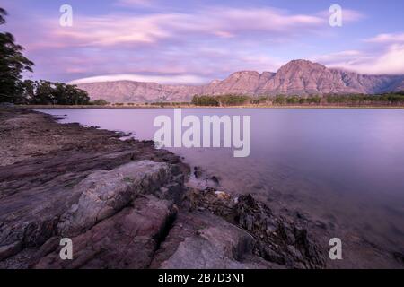Ein Landschaftsfoto einer schönen Bergkette nach Sonnenuntergang, mit einem See im Vordergrund, aufgenommen am Westkaper, Südafrika Stockfoto