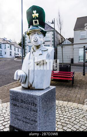 Ardara, County Donegal, Irland. März 2020. Die Büste des berühmten irischen Geige Spieler, John Doherty, ist mit Maske und Hut verspottet die aktuelle Coronavirus, Covid-19, Pandemie geschmückt. Die St. Patrick's Day Parade der Stadt wurde zusammen mit den meisten solchen Paraden in Irland abgesagt. Stockfoto