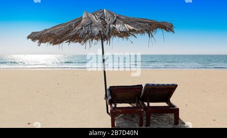 Sonnenschirme und Lounge-Stühle in einem Strandcafé am tropischen, sonnigen Strand in GOA, Indien Stockfoto