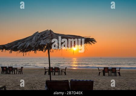 Sonnenuntergang in Lounge-Stühlen mit Sonnenschirmen an einem tropischen sonnigen Strand in GOA, Indien Stockfoto