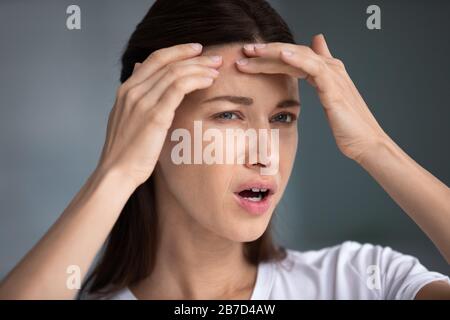 Betonte frustrierte junge Frau, die sich Sorgen über Hautprobleme macht. Stockfoto