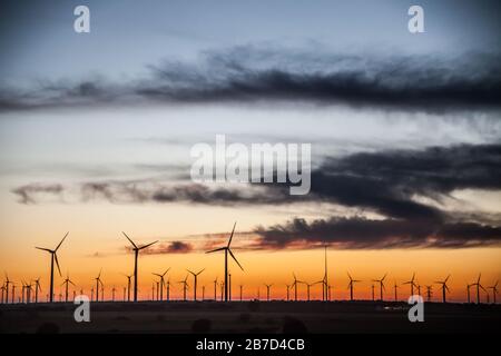 Sonnenuntergang bei Windgeneratoren Feld mit blauem und orangefarbenem Himmel Stockfoto