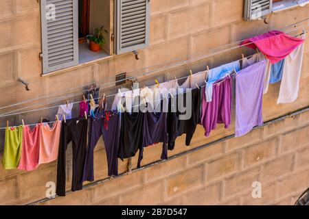 Nasswäsche Trocknen draußen auf Waschstraßen unter Fenstern einer Wohnung im historischen Zentrum von Siena, Toskana, Italien. Stockfoto