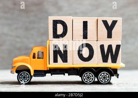 LKW hält Buchstabenblock im Wort DIY (Abkürzung von Do IT Yourself) jetzt auf Holzhintergrund Stockfoto