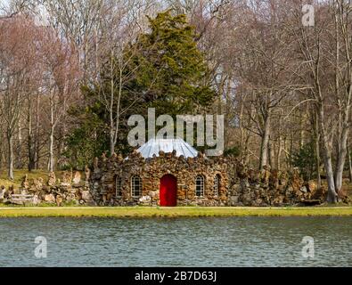 Gosford Estate, East Lothian, Schottland, Großbritannien. März 2020. Großbritannien Wetter: Frühlingssonne auf dem Landgut. Die schrullige Steinkräuselhütte, die über den künstlichen See gesehen wurde Stockfoto