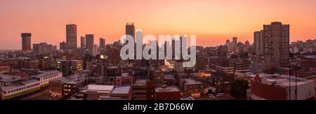 Ein wunderschönes und dramatisches Panorama-Foto der Skyline der Stadt Johannesburg, aufgenommen an einem goldenen Abend nach Sonnenuntergang. Stockfoto