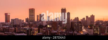 Ein wunderschönes und dramatisches Panorama-Foto der Skyline der Stadt Johannesburg, aufgenommen an einem goldenen Abend nach Sonnenuntergang. Stockfoto