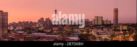 Ein wunderschönes und dramatisches Panorama-Foto der Skyline der Stadt Johannesburg, aufgenommen an einem goldenen Abend nach Sonnenuntergang. Stockfoto