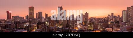 Ein wunderschönes und dramatisches Panorama-Foto der Skyline der Stadt Johannesburg, aufgenommen an einem goldenen Abend nach Sonnenuntergang. Stockfoto