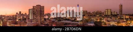 Ein wunderschönes und dramatisches Panorama-Foto der Skyline der Stadt Johannesburg, aufgenommen an einem goldenen Abend nach Sonnenuntergang. Stockfoto