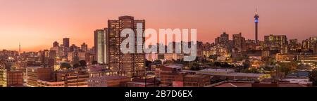 Ein wunderschönes und dramatisches Panorama-Foto der Skyline der Stadt Johannesburg, aufgenommen an einem goldenen Abend nach Sonnenuntergang. Stockfoto