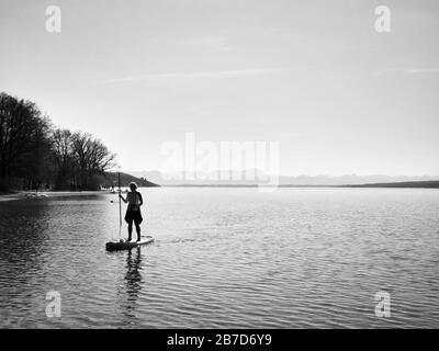 Starnberg, Bayern, Deutschland. März 2020. Ein Stand-Up-Paddler am Starnberger See bei München übt soziale Distanzierung und schmeichelt die Kurve beim Ausbruch des europäischen Coronavirus und nachfolgende Maßnahmen zur Kontrolle der Ausbreitung. Credit: Sachelle Babbar/ZUMA Wire/Alamy Live News Stockfoto