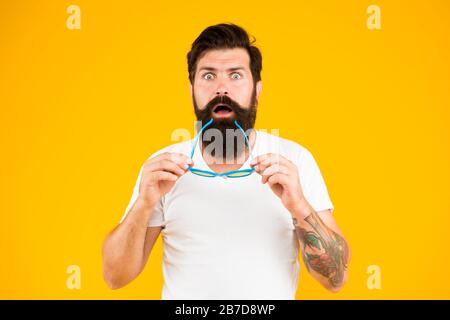 Super verrückte Überraschung. Verrückte Hüfte halten Mund offen gelber Hintergrund. Überraschter bärtiger Mann hält Brille mit verrücktem Look. Barbershop. Mode und Stil. Verrückt und schockierend. Stockfoto