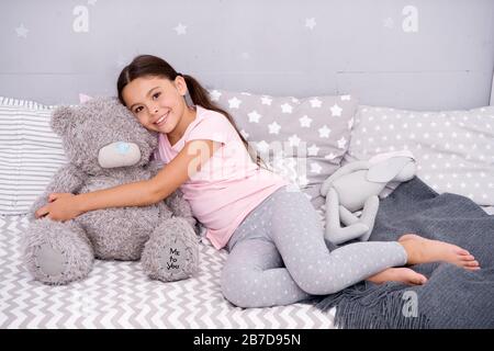 Ideal zum Kuscheln. Glückliches Kind hält Teddybärspielzeug im Bett. Kleine Mädchen spielen mit weichem Spielzeug. Spielwarenladen oder -Geschäft. Kinderspielzeug. Spielzeit. Kindheitsspiele. Stockfoto