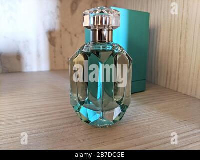 Glas-Parfümflasche vor türkisfarbenem Kastenverpackungen isoliert auf einem Holzregal Stockfoto