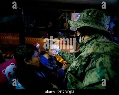 Philippinen. März 2020. Philippinen. März 2020. (15.3.2020) Pendler an Bord von Pacita, San Pedro, Laguna - Navotas Bus Route schaut auf den ermüdungsbekleideten Polizisten, als sie in ihren Bus am Susanna Exit, NCR Community Quarantine Checkpoint einsteigen. Ab heute gibt es verschiedene Kontrollpunkte an den wichtigsten und strategischen ein- und Ausgängen der Metro Manila, Maßnahmen wie diese werden ergriffen, um zu verhindern, dass die Ausbreitung von Covid-19 durch die Kontrolle der Bewegung und der Reisen von Menschen verhindert wird. Kredit: SIPA USA/Alamy Live News Stockfoto