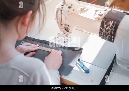 Näherungsmessstück aus Stoff, Schulteransicht. Needlefrau an der Übersperr-Nähmaschine, die professionelle Arbeit leistet, Arbeitskonzept Stockfoto