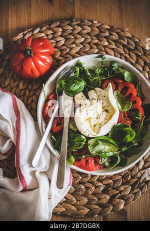 Flat-lay von traditionellem italienischem Salat mit Buratta-Käse, Tomaten, Arugula und frischem Basilikum, Draufsicht. Konzept der klassischen italienischen Küche Stockfoto