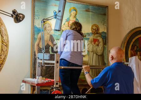 Ein Restaurator, der an einem mittelalterlichen Gemälde in Pinacoteca arbeitet, einem kunsthistorischen Museum im Palazzo Comunale an der Piazza del Duomo in San Gimignano. Stockfoto