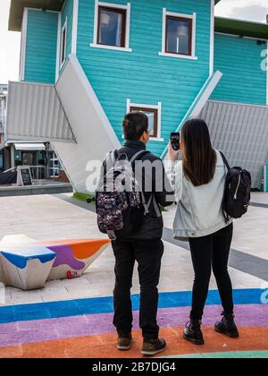 Zwei Touristen fotografieren das kopfüber gelegene Haus, Touristenattraktion an der Brighton Seesfront Stockfoto