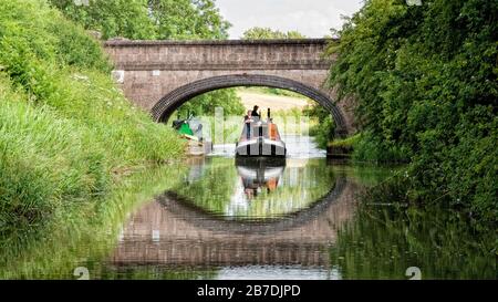 Schmalbootfahrt unter einer bogenförmigen Brücke auf dem Grand Union Canal Leicester Arm, England, Großbritannien, Leicestershire Stockfoto