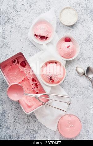 Rosa Eiscreme mit Himbeeren und roten Korinsen. Draufsicht mit Eisschaufel Stockfoto