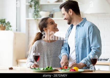 Fröhliches junges Paar, das zusammen in der Küche Abendessen kocht Stockfoto