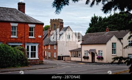 Reihe von Reihenhäusern mit Strohdächern und Kirchturm in Welford, England, Großbritannien, Leicestershire, Stockfoto