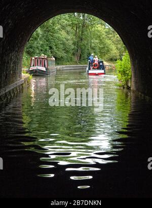 Schmalboote verlassen den Braunston Tunnel auf dem Grand Union Canal, Warwickshire, während ein Leihboot auf den Eintritt wartet, Braunston, England, Großbritannien Stockfoto