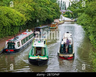 Zwei Kreuzfahrtschmalboote, die auf dem Grand Union Canal, Warwickshire, England, Großbritannien, angelegte Boote passieren Stockfoto