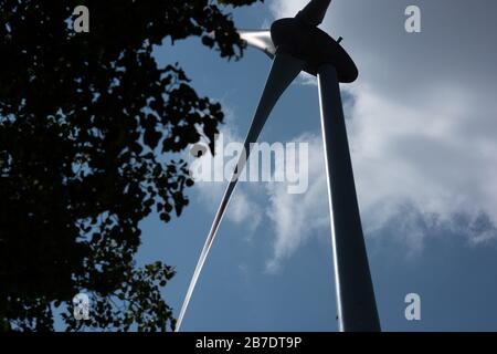 Nachhaltige Stromerzeugung mit an- oder Offshore-Windenergieanlagen, die gegen die Sonne und auf moderne Weise erfasst werden und auf Rotor und Mast blicken Stockfoto
