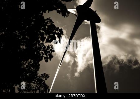 Nachhaltige Stromerzeugung mit an- oder Offshore-Windenergieanlagen, die gegen die Sonne und auf moderne Weise erfasst werden und auf Rotor und Mast blicken Stockfoto