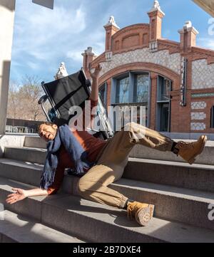 Behinderter Latino-junger Mann im Rollstuhl fällt eine Treppe hinunter, die er nicht mit dem Stuhl auf der Straße hinuntergehen kann Stockfoto