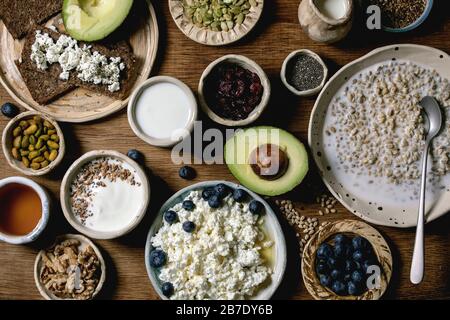 Gesundes Frühstück. Verschiedene Frühstücksküche mit gerountem Weizen, Joghurt, Kefir, Hüttenkäse, Avocado, Roggenbrot, Samen, Nüssen und Beeren Sortiment i Stockfoto