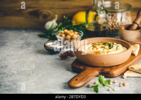 Hummus. Große Schüssel hausgemachter Hummus garniert mit Kichererbsen, rotem süßen Pfeffer, Petersilie und Olivenöl, mittelöstlicher Küche, Kopierraum Stockfoto